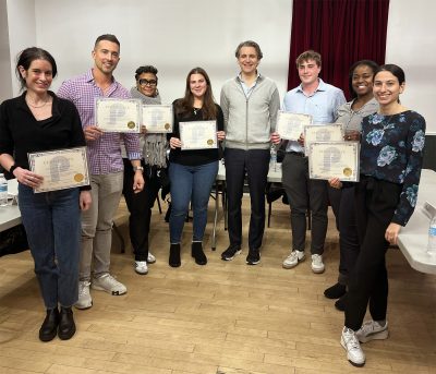 The students are holding up their certificates at the end of Herman's public speaking class.